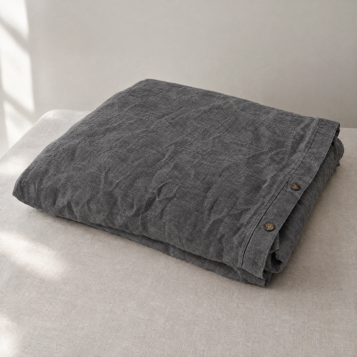 Stonewashed linen duvet cover in Charcoal, folded with coconut-shell buttons