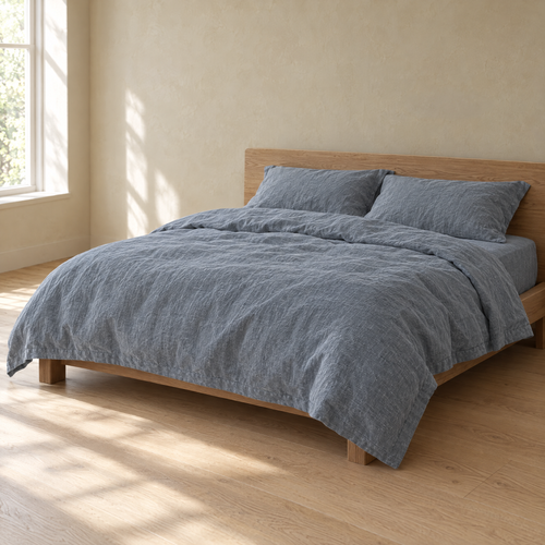 Bed made with a Dusk linen duvet cover in a plain bedroom